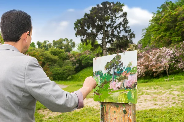 Back view of a male artist working outdoors in the park or garde