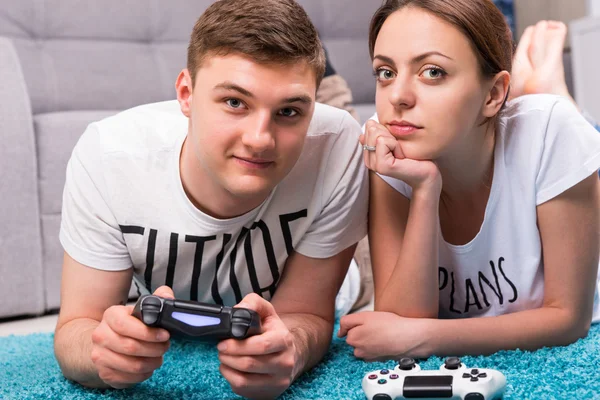 Attractive pair lying on a rug playing video games