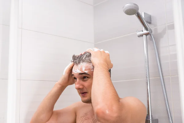 Young man washing his hair in shower