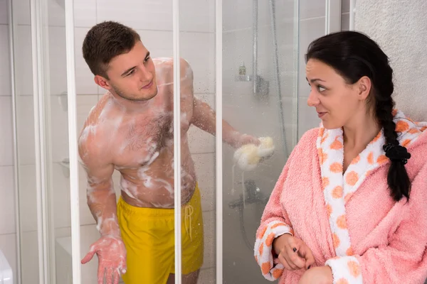 Woman in bathrobe points to husband that it\'s her turn to have a