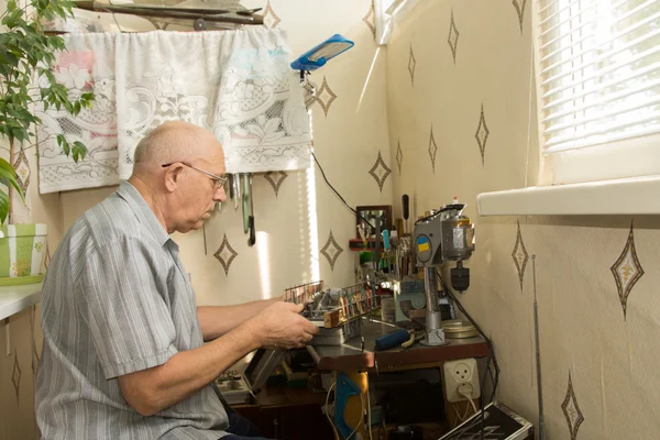 Retired man working at home on his handicrafts
