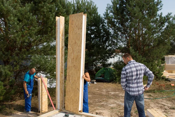 Builders aligning insulated wall panels