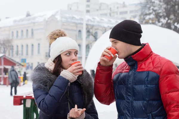 Couple sipping hot drinks in a wintry town square