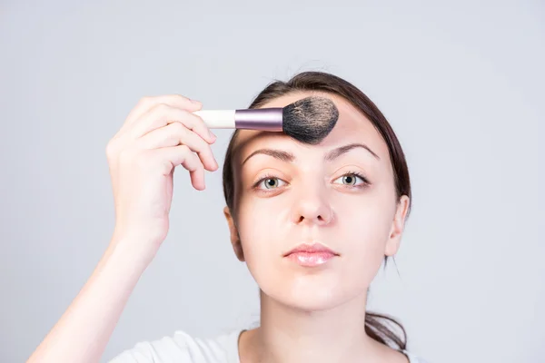 Young Woman Applying Foundation Makeup on Forehead