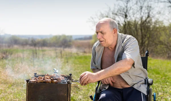 Aged Man on his Wheelchair Grilling Under the Sun