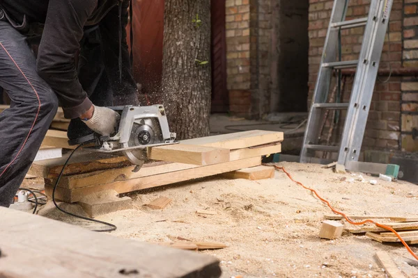 Man Using Power Saw to Cut Planks of Wood
