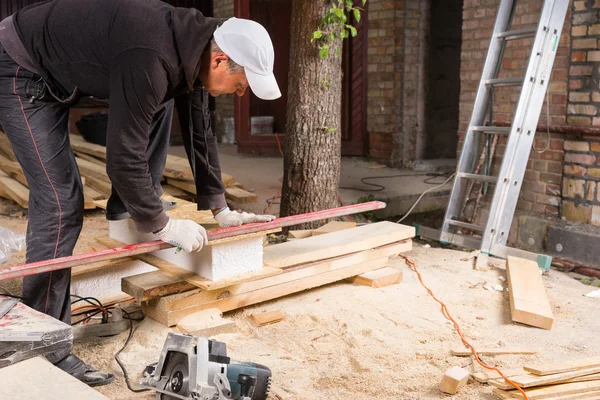 Man Using Power Saw to Cut Planks of Wood