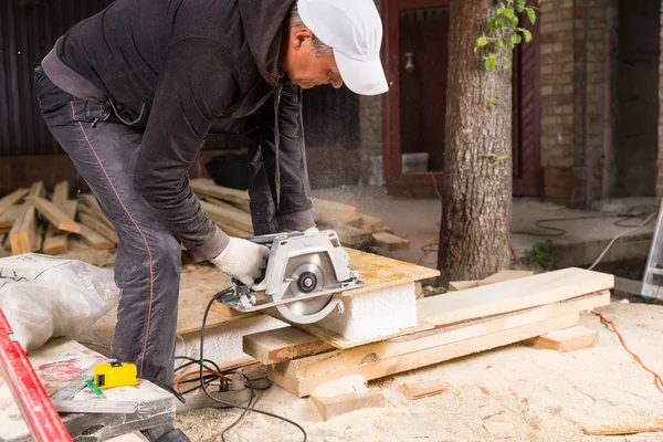 Man Using Power Saw to Cut Planks of Wood