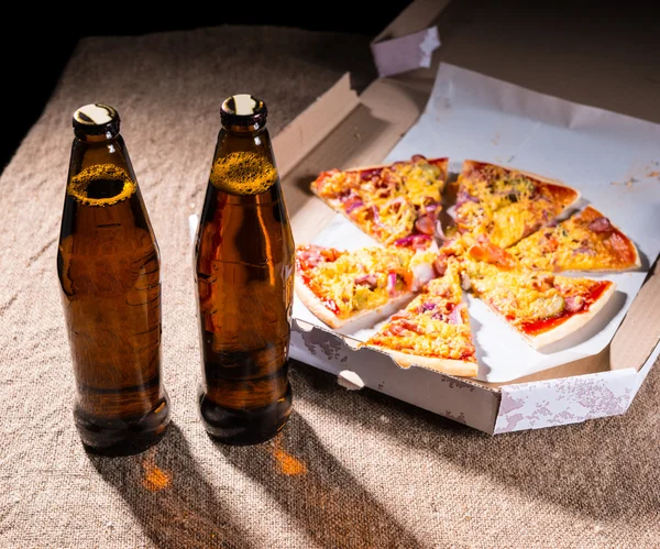 Bottles of Beer and Pizza in Box on Table