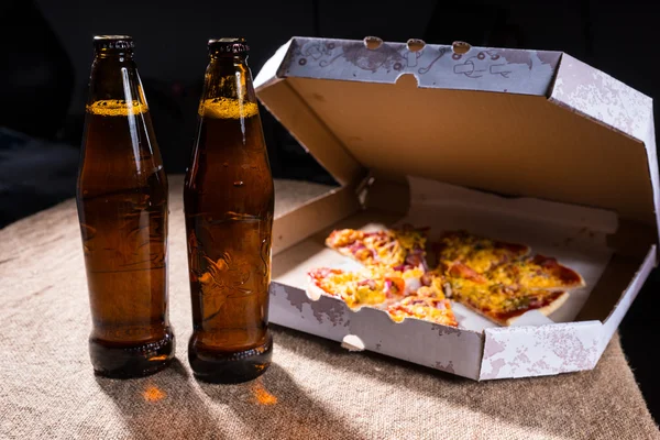 Beer Bottles on Table by Pizza Box with Open Lid