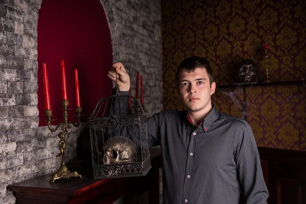 Young Man Holding Skull in Cage Inside Castle