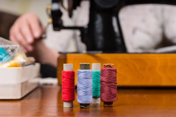 Spools of Thread on Table by Sewing Machine