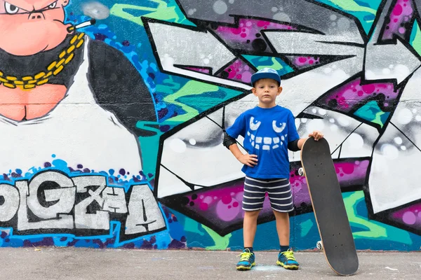 Boy with Skateboard in front of Graffiti Wall