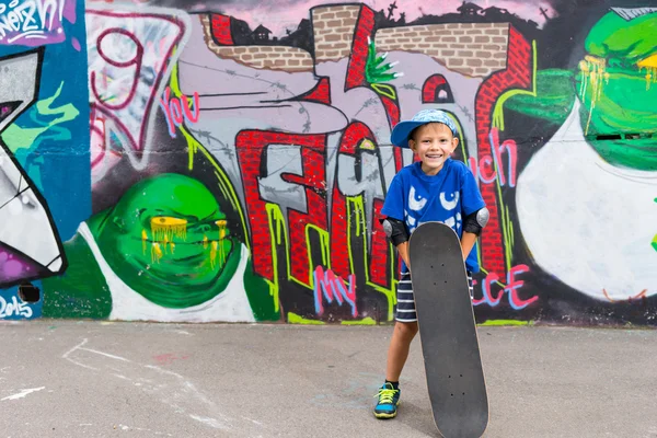 Smiling Boy Standing with Skateboard in Skate Park