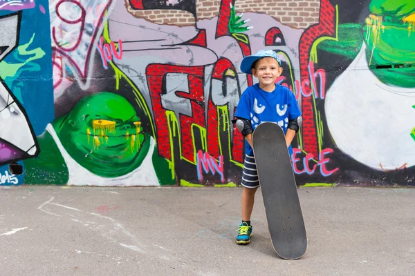 Smiling Boy Standing with Skateboard in Skate Park