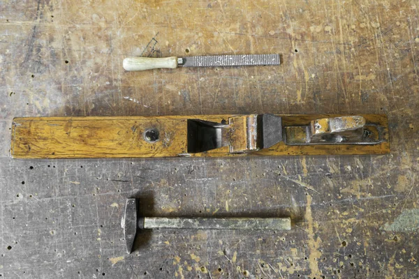 Old carpenter tools planer, hammer and rasp on vintage wooden ba