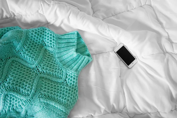 Female outfit and smartphone laid out on bed, morning light