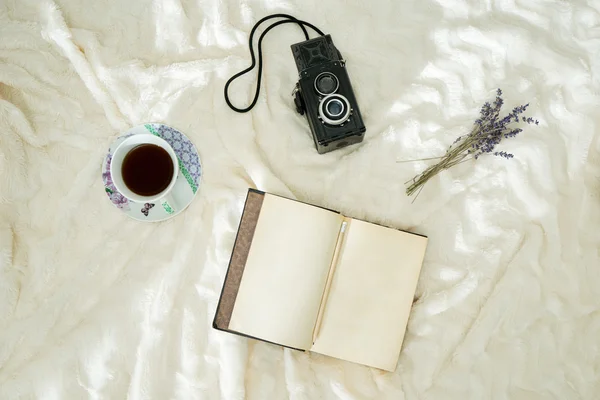 Cup of coffee, dry lavender, vintage notebook and camera over wh