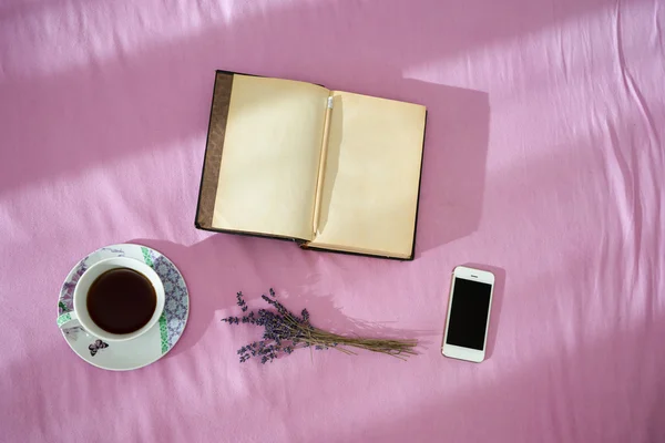 Cup of coffee, dry lavender, vintage notebook and smartphone ove