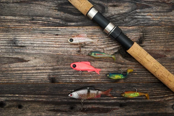 Spinning rod, reel and fishing baits isolated on wooden backgrou