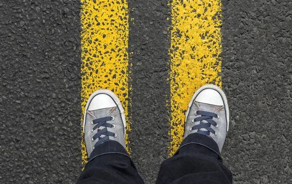 Standing on yellow street lines.