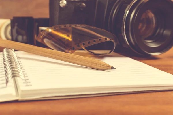 Old SLR camera on the table next to negative film strip, and in