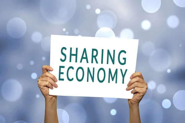 SHARING ECONOMY card in hand with abstract light background.