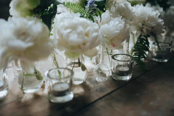 White peonies in glass bottles