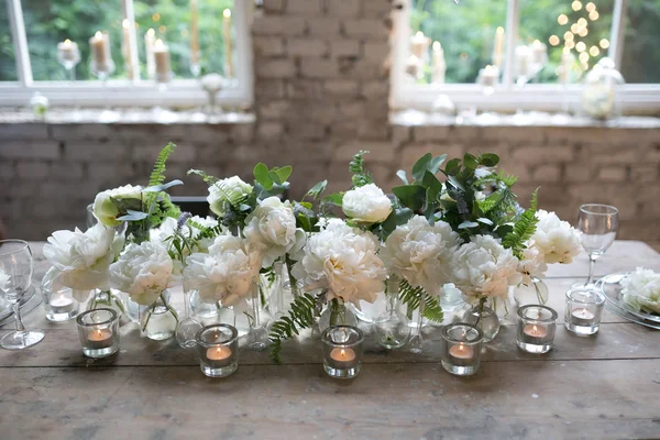 White peonies in glass bottles