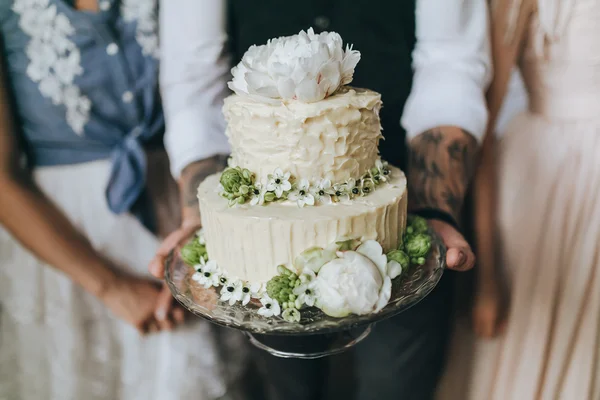 Couple holding white wedding cake