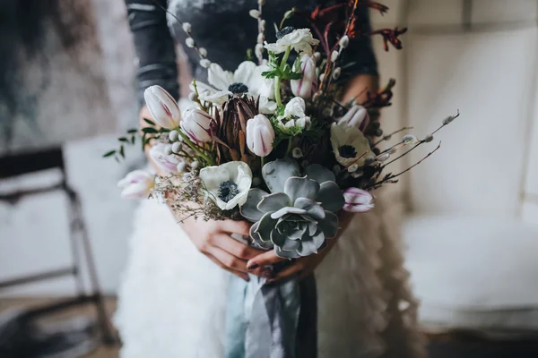Bride holding bouquet of flowers and greenery