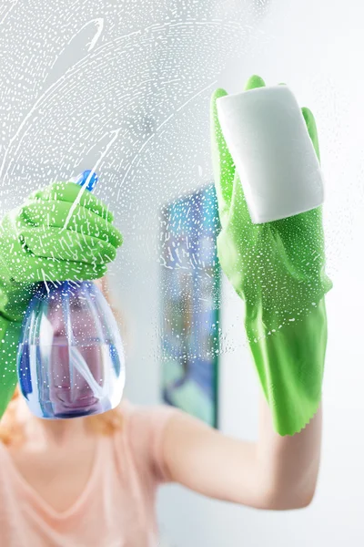 Woman cleaning window pane with detergent, cleaning concept