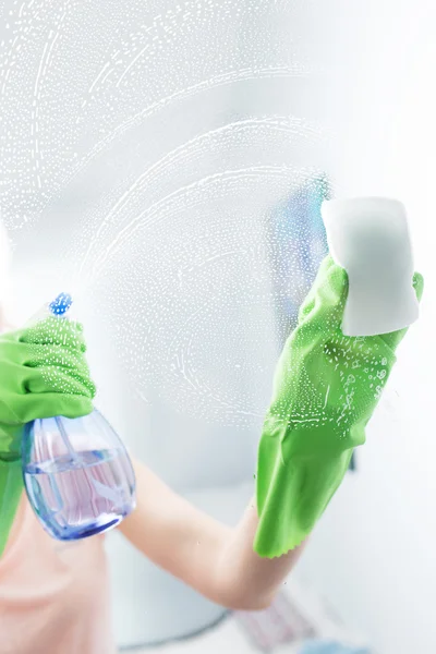 Woman cleaning window pane with detergent, cleaning concept