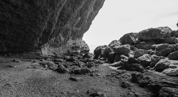 Secluded cove with huge coastal rocks, black and white photo
