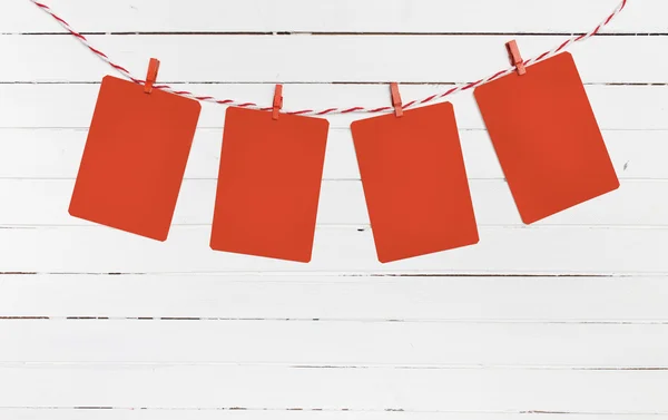 Blank paper or photo frames hanging on the red striped clothesline . Wooden background. Template for your text.