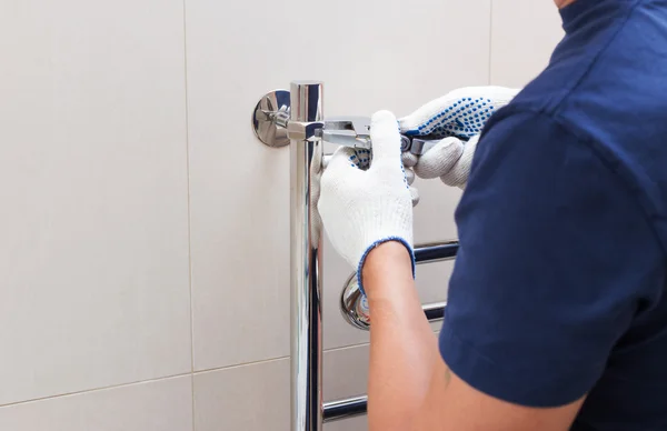 Plumber fixing chrome heated towel rail in bathroom