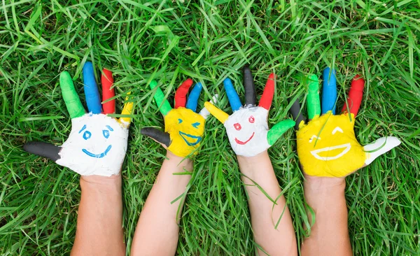 Colored hands with smile painted in colorful paints against gree