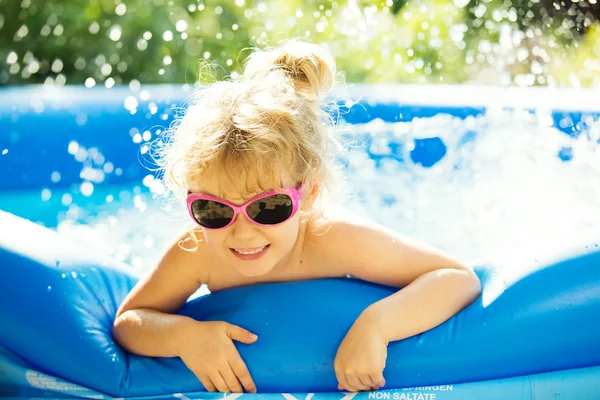 Happy girl playing in blue swimming pool. Summer holidays.