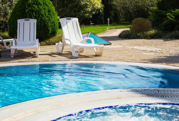 Plastic white sunbed near pool, green on background