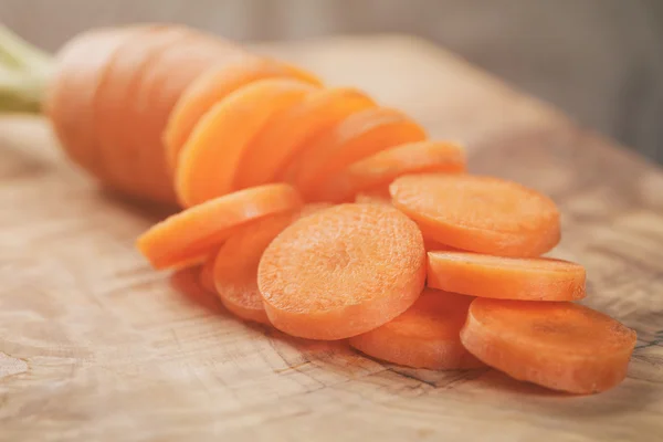Sliced organic carrot on olive wood cutting board closeup photo
