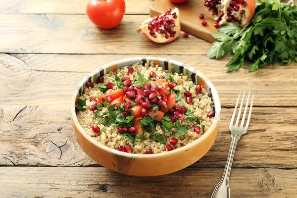 Quinoa salad with tomato and pomegranate in ceramic bowl