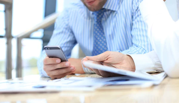 Smartphone handheld in closeup, colleagues working in background