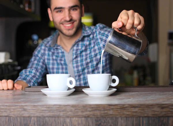 Selective focus on two white cups of coffee and metal jar with milk