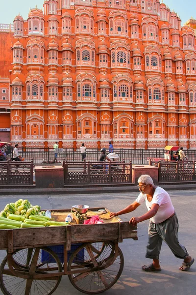JAIPUR, INDIA - NOVEMBER 13: Unidentified man walks with cart near Hawa Mahal on November 13, 2014 in Jaipur, India. Hawa Mahal was designed by Lal Chand Ustad in the form of the crown of Krishna