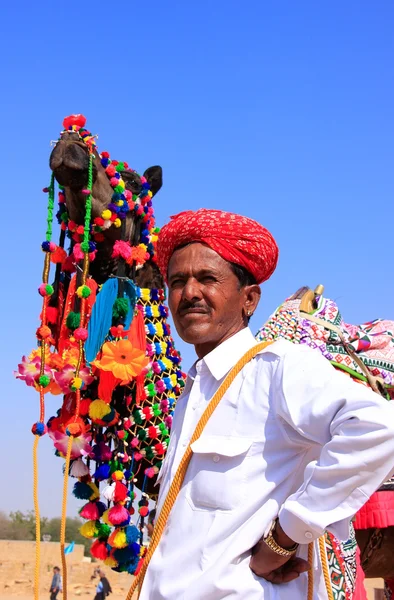 Indian man standing with his decorated camel at Desert Festival,