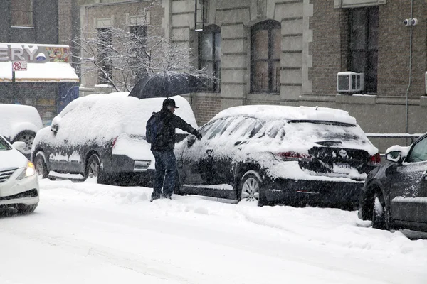 Man cleans car during snow storm