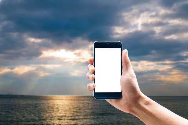 Hand using smartphone mobile in the vertical position, blur the background of the sea.