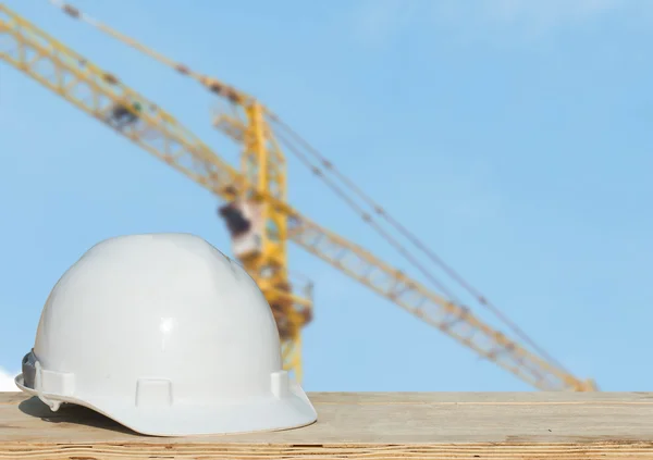 Safety helmet and architect plant on wood table with  building construction