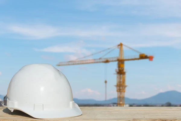 Safety helmet and architect plant on wood table with  building construction