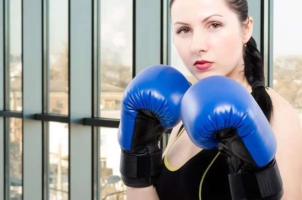 Portrait of a young beautiful woman in boxing gloves in the gym
